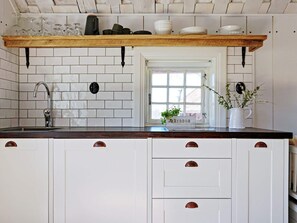 A kitchen with white cabinets, a wooden countertop, and a window with a view. - 5 Person Holiday Home in Mellosa (Flen)