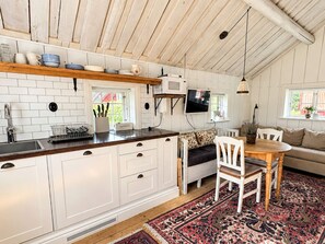 A kitchen with white cabinets, a wooden countertop, and a dining area with a table and chairs.
