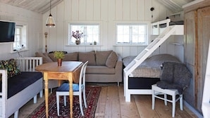 A cozy cabin interior with a wooden dining table, a sofa, a staircase, and a television. - 5 Person Holiday Home in Mellosa (Flen)
