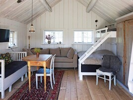 Un acogedor interior de cabaña con una mesa de comedor de madera, un sofá, una escalera y un televisor.