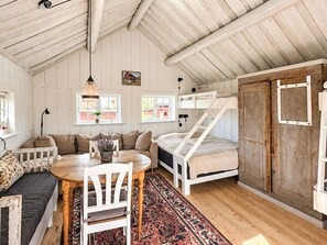 A cozy cabin interior with a loft bed, a dining area with a table and chairs, and a sofa.