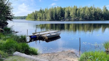 A calm lake with a dock and a boat, surrounded by dense forest.