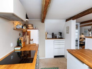 A compact kitchen with wooden countertops, a built-in stove, and white cabinetry.