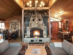 A rustic interior with a stone fireplace, wooden ceiling, and a dining area with chairs and tables. - 51 Person Holiday Home in BOE Telemark (Midt-Telemark)