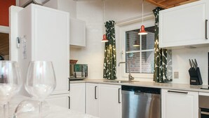 Eine moderne Küche mit weißen Schränken, Edelstahlgeräten und einem Fenster mit gemusterten Vorhängen.