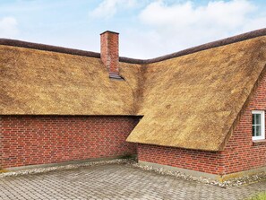 A brick building with a sloped roof covered in straw. - Holiday Home in Blåvand (Blavand)