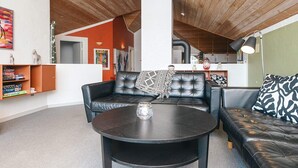 Ein modernes Wohnzimmer mit einer schwarzen Ledersofa, einem runden Couchtisch und einem Bücherregal.
