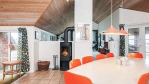 Eine moderne Küche mit einer zentralen Kochinsel, einem Essbereich mit orangefarbenen Stühlen und einem großen Fenster.