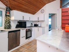 A modern kitchen with white cabinets, a black microwave, and a coffee maker. - Holiday Home in Blåvand (Blavand)