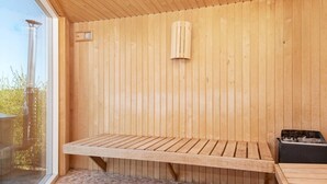 Eine Holzsauna mit Bank und kleinem Heizgerät.