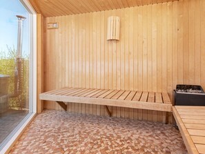 A wooden sauna with a bench and a small heater. - Holiday Home in Odder (Odder)