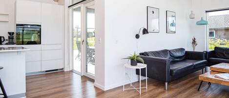 A modern living space with a kitchen, a dining area, and a seating area with a sofa and coffee table.