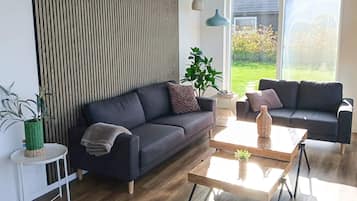 A modern living room with two sofas, a coffee table, and a side table with a plant.