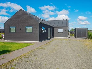 A modern building with a sloped roof, a large window, and a door. - Holiday Home in Odder (Odder)