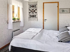 A bedroom with a bed, a window with curtains, a door, and a wall hanging. - 8 Person Holiday Home in Solleron (Sollerön)