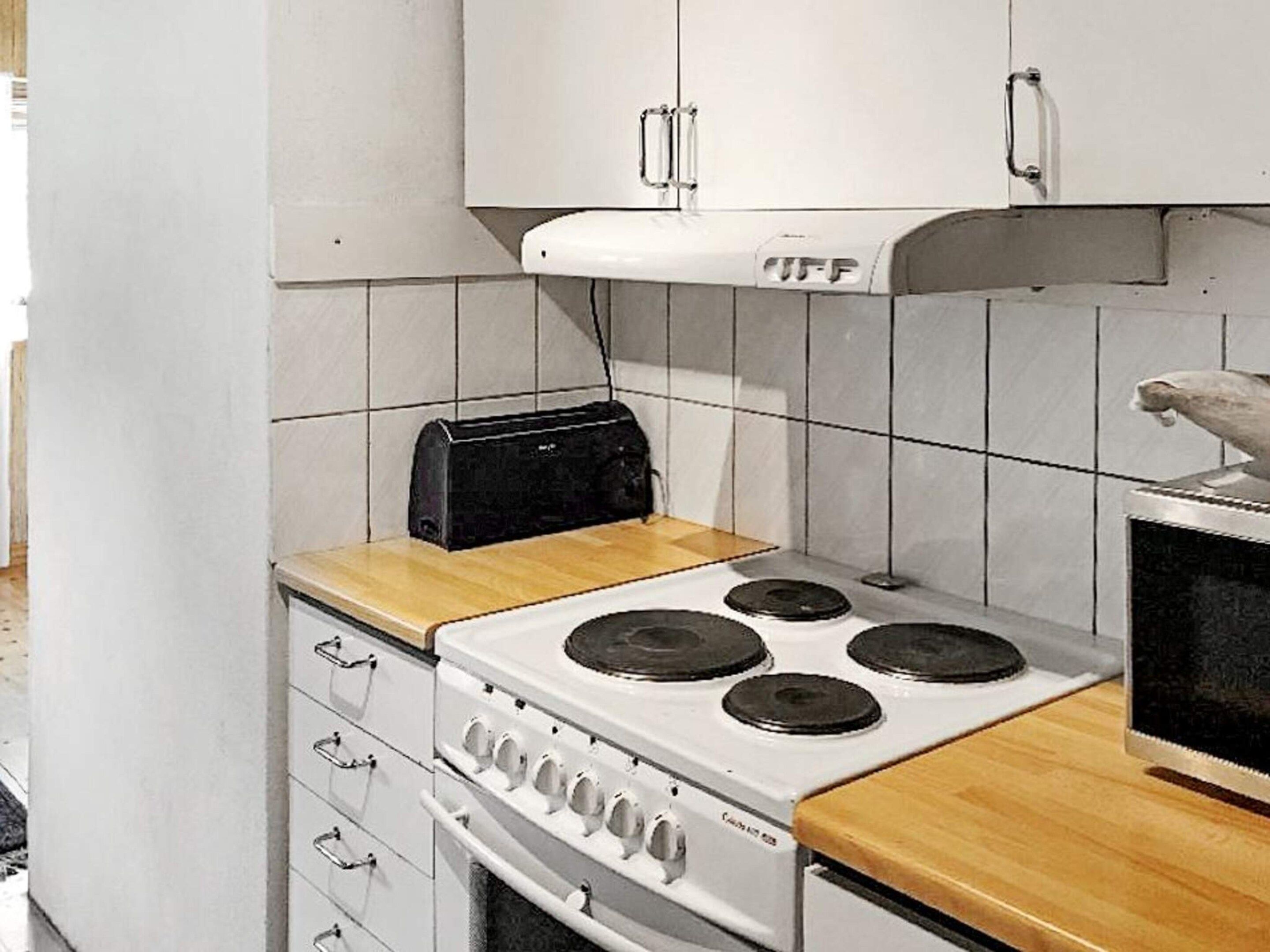 A compact kitchen with a white stove, a toaster, and a microwave.