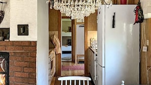 Uma cozinha acolhedora com frigorífico branco, luminária pendente e lareira de tijolos.