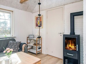 Een gezellige kamer met een houten tafel, een bank, een hanglamp, een boekenkast en een houtkachel.