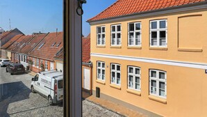 Ein gelbes Gebäude mit rotem Ziegeldach und weiß gefassten Fenstern.