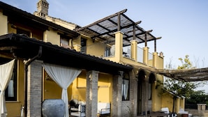 A two-story house with a patio area, outdoor seating, and a large planter. - Hillside Retreat in San Savino (Ripatransone)