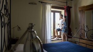 A bedroom with a bed, a window with curtains, a bedside lamp, and a wooden ceiling. - Hillside Retreat in San Savino (Ripatransone)
