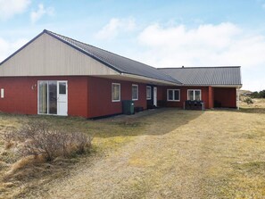 En enplansbyggnad med ett sluttande tak, en ytterdörr och en täckt veranda.