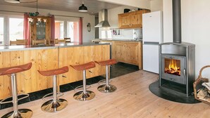 Una cocina moderna con armarios de madera, una isla central con taburetes altos, estufa e iluminación colgante.