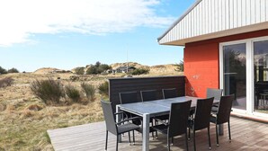 Una terraza con mesa y sillas, un muro rojo y vistas a una colina.