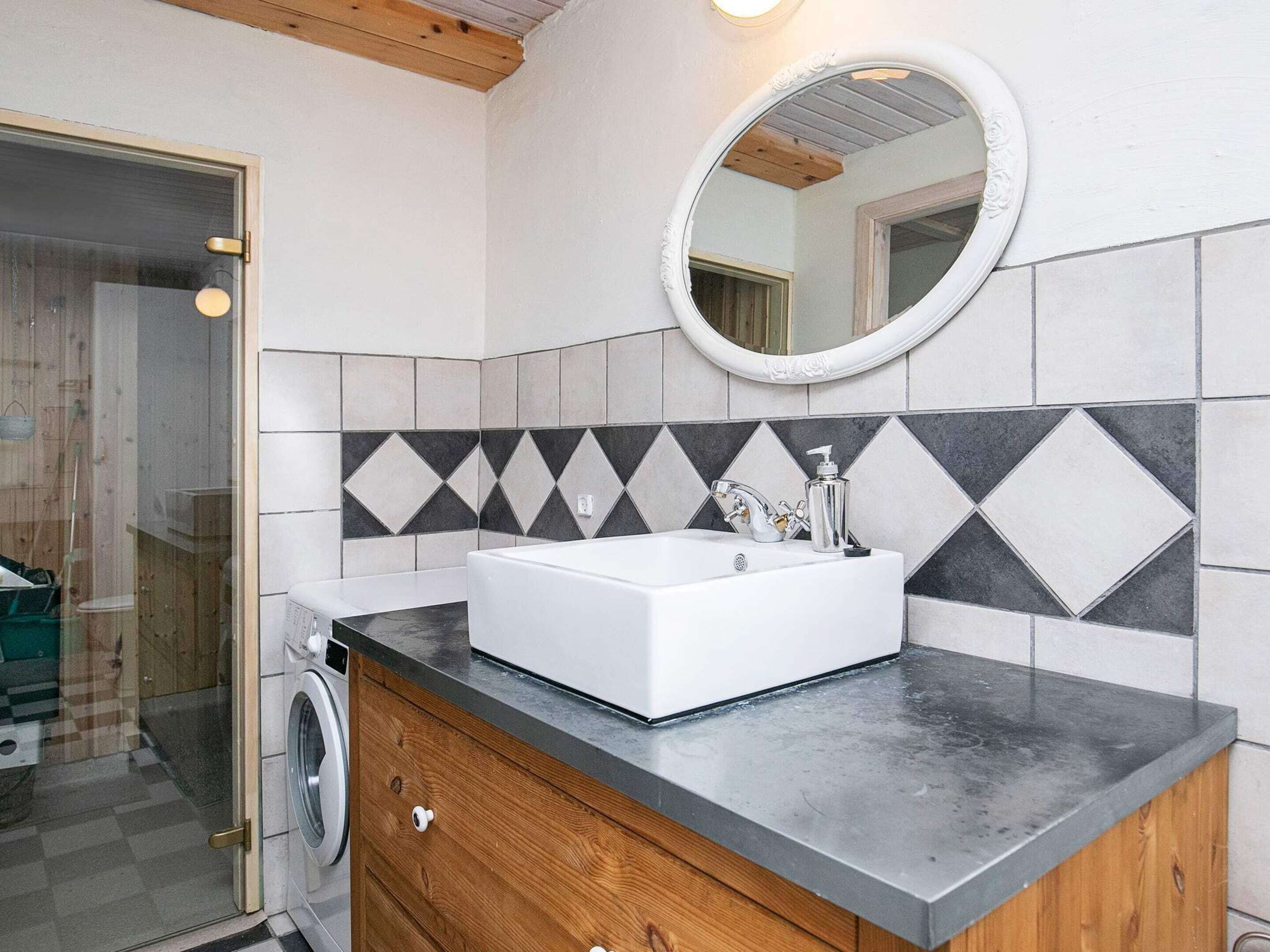 A bathroom with a white sink, a mirror, and a tiled backsplash.