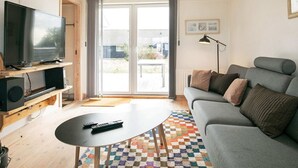 Una sala de estar con televisión, sofá y mesa de centro.