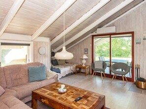 A cozy room with a wooden ceiling, a sofa, a coffee table, a bed, and a dining area with chairs. - 6 Person Holiday Home in Hemmet (Hemmet)