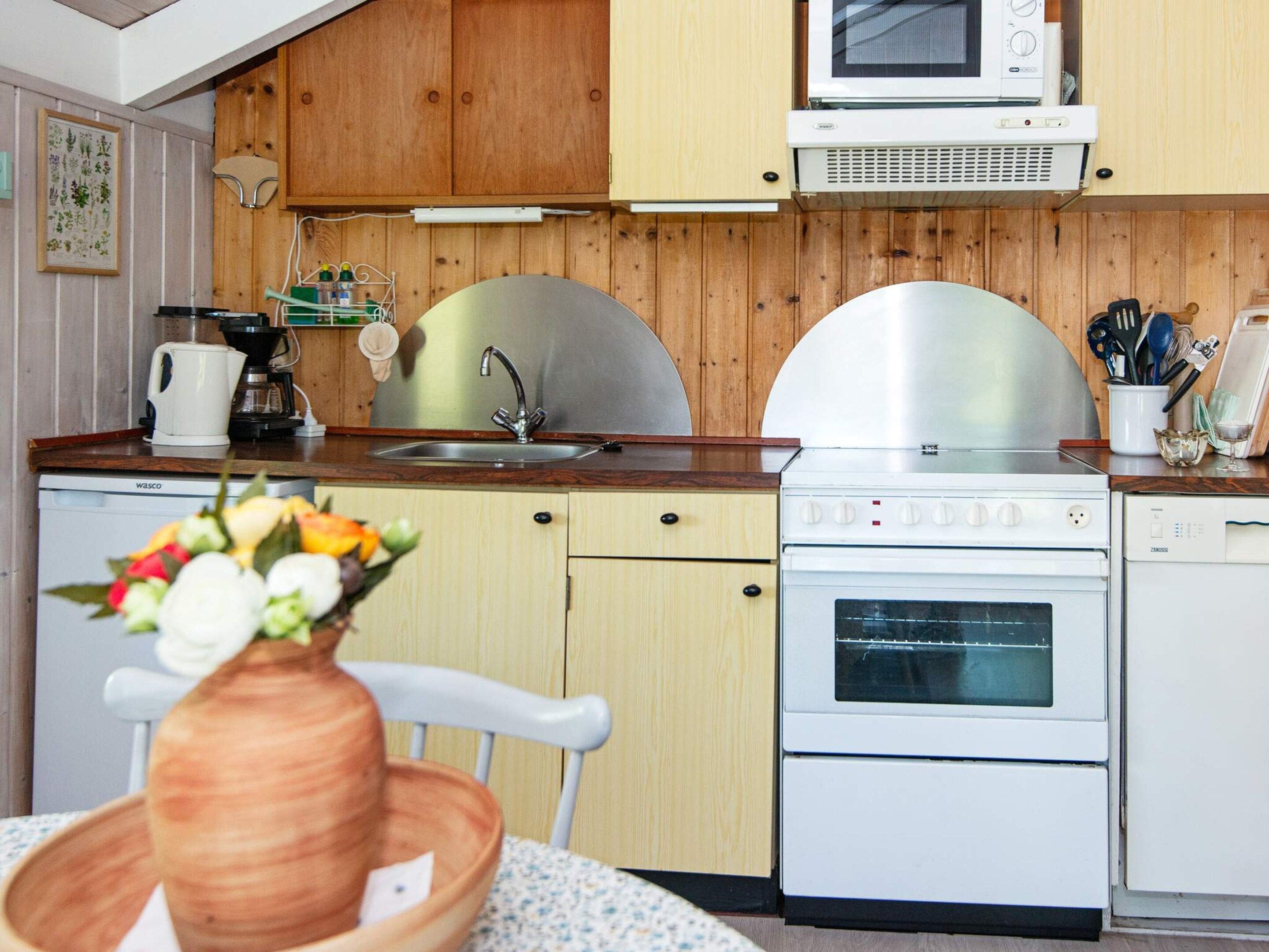 A kitchen with wooden cabinets, a microwave, a stove, and a sink.