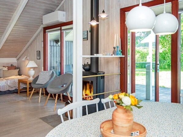 A cozy living room with a fireplace, a dining table with a vase, and a comfortable seating area. - 6 Person Holiday Home in Hemmet (Hemmet)