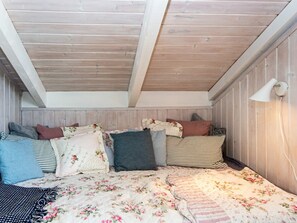 A bedroom with a wooden ceiling, a bed with floral bedding, and a bedside lamp. - 6 Person Holiday Home in Hemmet (Hemmet)
