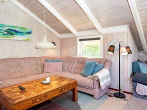 A cozy living room with a sectional sofa, a wooden coffee table with drawers, a floor lamp, and a painting on the wall. - 6 Person Holiday Home in Hemmet (Hemmet)