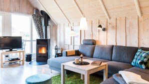 Ein gemütliches Wohnzimmer mit Kamin, einer Couch, einem Couchtisch und einem Fernseher.