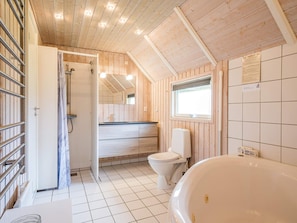 Ein kleines Badezimmer mit Holzvertäfelung, einer Dusche, Toilette und einem Waschbecken.