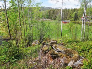 A forested area with a red building, likely a cabin or lodge, surrounded by trees and rocks. - 6 Person Holiday Home in Henan (Henån)