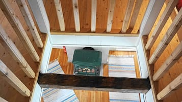 A room with a wooden floor, a green object on the floor, and a striped rug.