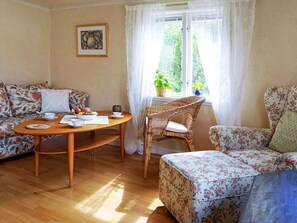 Un salon chaleureux avec une table basse en bois, un canapé à motifs floraux et un fauteuil en osier.
