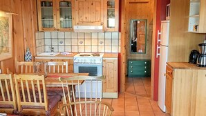 A cozy kitchen with wooden cabinets, a stove, and a dining area with chairs and a table. - 3 Person Holiday Home in BOE Telemark (Midt-Telemark)