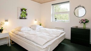A bedroom with a bed, bedside table, dresser, mirror, window, and artwork. - Holiday Home in BlÃ¥vand (Blavand)