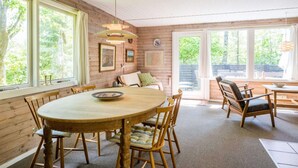 A wooden interior with a round dining table, chairs, and a large window. - 4 Person Holiday Home in Norre Nebel (Norre Nebel)