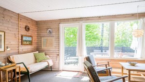 A cozy room with a wooden interior, a sofa, a dining table, and chairs. - 4 Person Holiday Home in Norre Nebel (Norre Nebel)