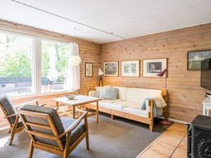 Une pièce chaleureuse avec un décor intérieur en bois, un canapé, une table et des chaises.