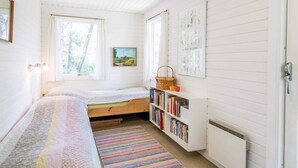 A cozy bedroom with a bed, a bookshelf, and a window. - 4 Person Holiday Home in Norre Nebel (Norre Nebel)