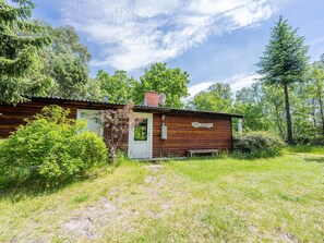 A rustic cabin with a wooden exterior, a white door, and a small porch area. - 4 Person Holiday Home in Norre Nebel (Norre Nebel)