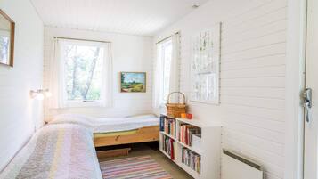 Un dormitorio con dos camas, una estantería y una ventana con cortinas.