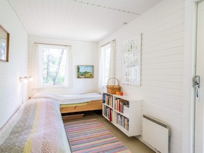 Un dormitorio con dos camas, una estantería y una ventana con cortinas.