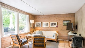 A cozy room with a wooden interior, a sofa, two chairs, a table, and a fireplace. - 4 Person Holiday Home in Norre Nebel (Norre Nebel)